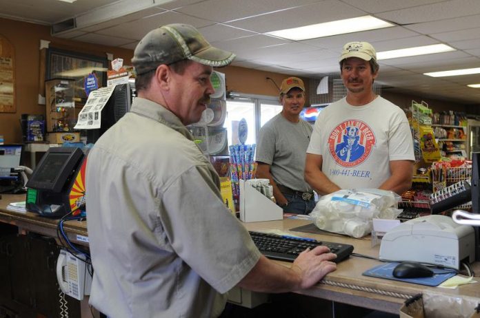 Tom Maxson, left, rings up a sale for brothers Paul, right, and George Stevick at a Camp Verde feed store Saturday, June 12. Residents could see two sales tax increases on a ballot in November.