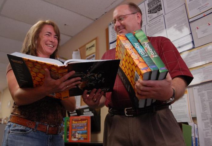 New Mingus Union High School Principal Tamara Addis and school district Business Manager Kirk Waddle look at the new mathematics textbooks May 26 which, pending school board approval sometime later this summer, could be adopted by the MUHS district thanks to funding from the passage of Proposition 100. The books are on display in the district office for parents to examine.