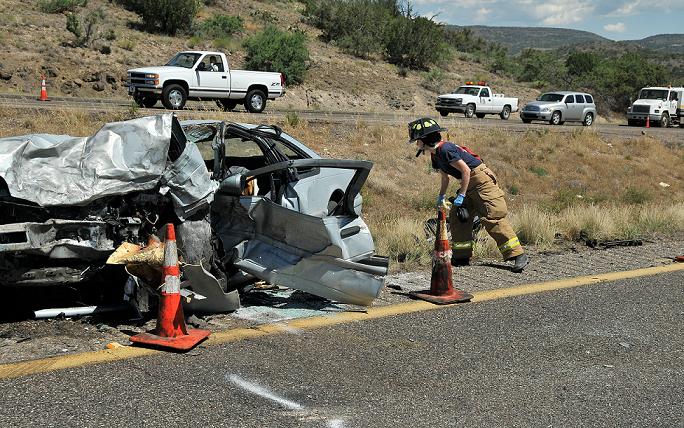 A firefighter with the Montezuma-Rimrock Fire Department looks over the wreckage of a Ford Thunderbird after its driver hit another vehicle head-on.
