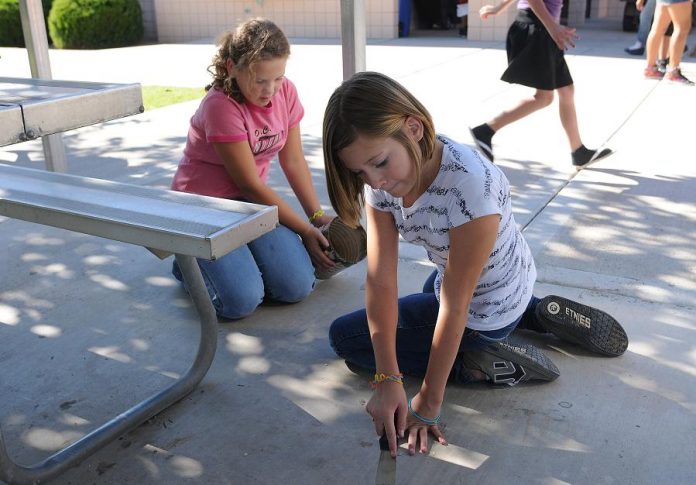 Ciara Francisco, right, and Alex Tacner scrape gum from the pavement on the Camp Verde Middle School campus Sept. 29.