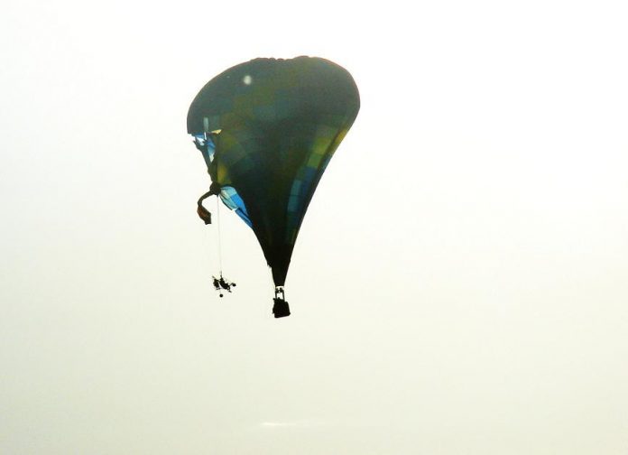 A paraplane dangles from a hot air balloon as both rapidly descend after colliding above the Cottonwood Airfest around 8 a.m., Oct. 16.