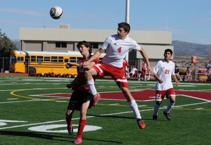 Marauders midfielder Alex Hickey knocks a Sand Devils player aside to get control of the ball during a Mingus Union High School home game against Page High School on Saturday, Jan. 22.