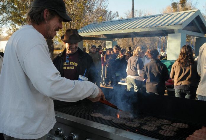 Shawn Corbin, a pastor at New Hope Christian Fellowship, grills cheeseburgers at Riverside Park on Friday, Feb. 4. Area Christian churches sponsor a free meal for anyone at the Cottonwood park every Friday night. The city raised concerns about the gathering, which operates under park ramadas Fridays at 5 p.m., because city ordinances require the host of such an event to have liability insurance to protect the city from lawsuits.