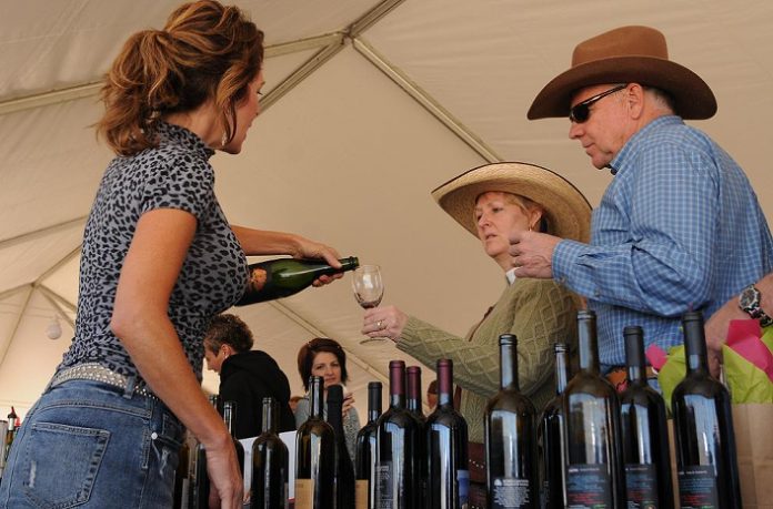 Jeanie Rowell, center, and her husband, Courtney Rowell, right, accept a glass of pecan champagne from pourer Linda Filandrinos at the Pecan, Wine and Antique Festival. “It’s delicious,” said Jeanie Rowell. “Delicate and sweet flavor followed by a pecan essence.”