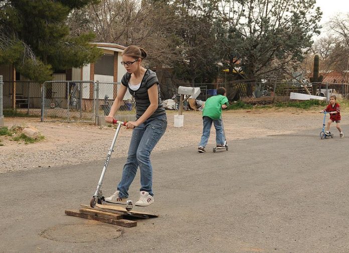 Summer Breeze, 16, left, rides her scooter with other children on North 11th Street on Monday, March 14. Cottonwood City Council voted Tuesday, March 8, to declare the neighborhood a redevelopment area.