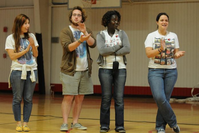 Representatives from Invisible Children, from left, Mia Pokriefka, Alex Naser-Hall, Aahola Agnes and Natalie Semotievle, applaud the efforts of Cottonwood Middle School students to raise money for former Ugandan child soldiers. Students attended an assembly held to teach more about the conflict Thursday, April 14.