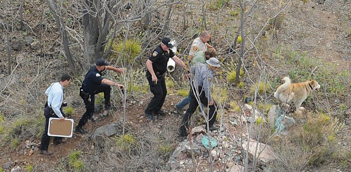 Police officers lead a mentally ill man who had been refusing to leave the entry to the Columbia mine shaft in Jerome up a steep hill to waiting police cars Thursday, April 7. The man allegedly escaped from a Cottonwood mental health facility on Wednesday, April 6