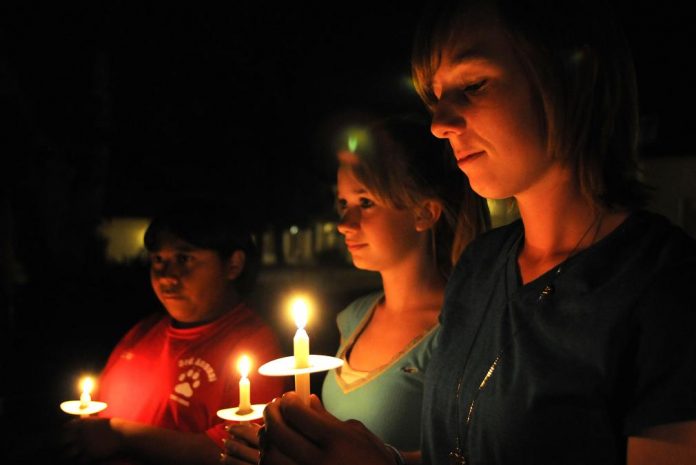 Skylar Martinez, right, and dozens of other Cottonwood Middle School students and their families solemnly observe a moment of candlelit silence to honor all those who suffer under tyranny at the school’s Day of Remembrance event Thursday, May 5.