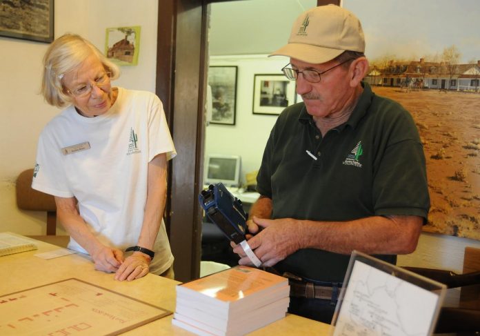 Fort Verde State Historic Park volunteers Paul Bueker and Dotty Bast price books while staffing the front desk Thursday, June 23. The Town of Camp Verde is considering changes to an existing agreement with the fort which currently has the state providing one and a half paid positions for the park supplemented by approximately 30 volunteers.