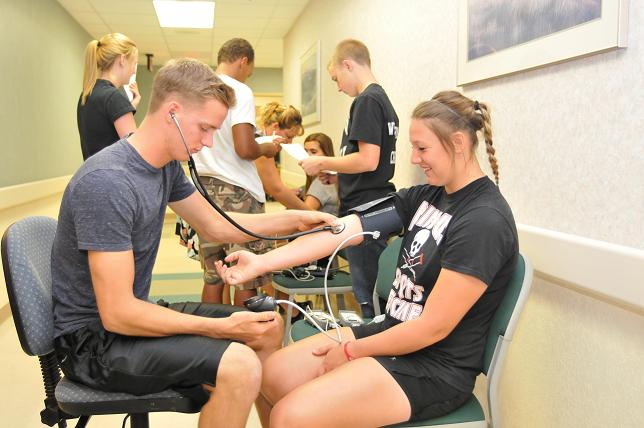 Mingus Union High School sports medicine student and volunteer Ryan Talbot, left, checks Heather Calandra’s cardio level.