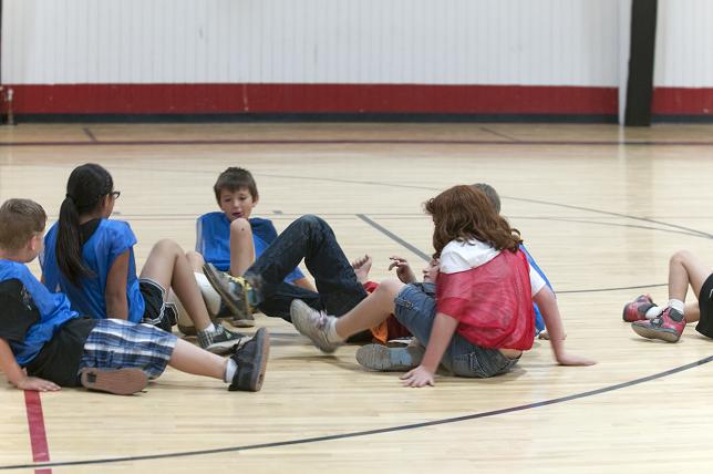 Kristopher Card, center, tries to kick a soccer ball with a group of kids during a game of crab soccer at the Fit Kids Summer Camp on Thursday, June 6, at the Cottonwood Middle School gym. Fit Kids of Arizona hosted its fourth annual summer camp last week with numerous activities such as sports, games, hikes, swimming and field trips to keep kids active and healthy.