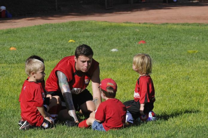 British Soccer Camp coach Dan Walmsley gets down at eye level with a group of kids at the camp Tuesday, July 30 at Riverfront Park in Cottonwood.