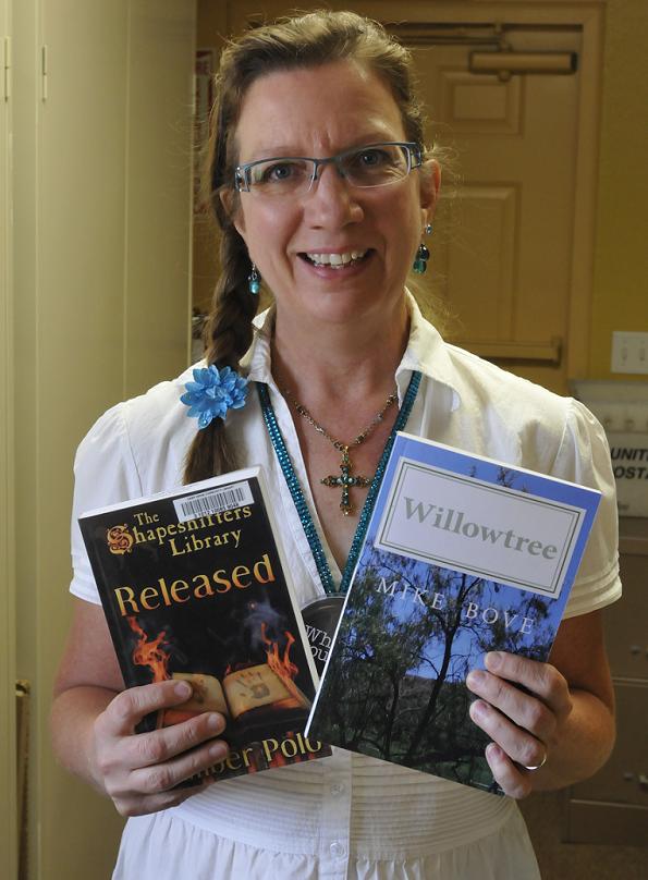 Kathy Hellman of the Camp Verde Public Library on Saturday, Aug. 17, holds two books by local authors, “Released: The Shapeshifters’ Library, Vol. 1,” by Amber Polo and “Willowtree” by Mike Bove.