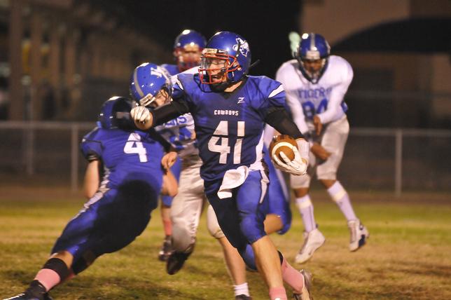 Tyler Dickey runs away from tacklers in the Cowboys game against Kingman Academy.