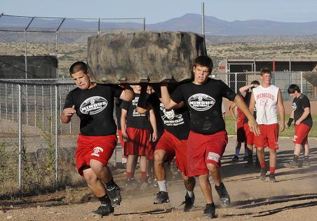 After the tire-flipping relay during a Big Man competition Thursday, June 19, at Mingus Union High School, one of three Marauders teams hoist the tire on their shoulders to run down a lane, around a barrel and back again, rushing to catch up with the team from Sedona Red Rock High School.