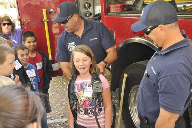 Although water is one of the main tools used to battle blazes for firefighters, Fire Marshal Rick Contreras, left, and Fire Inspector Steve Trantman, of the Cottonwood Fire Department, show students some of the other tools used. Karlee Dabbs got to suit up with an air tank firefighters use in smoky conditions. Fourth-graders from around the Verde Valley took part in a water conservation workshop put on by AZ Project Wet at Dead Horse Ranch State Park.