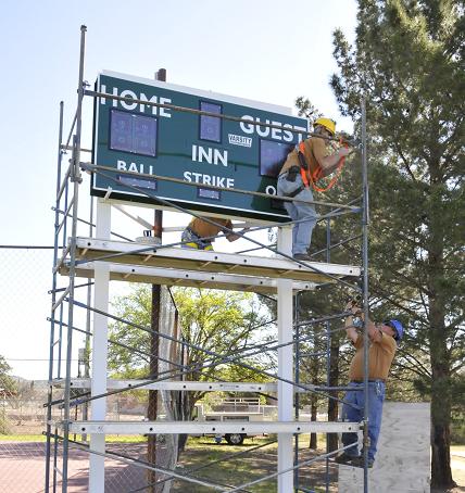 Butler Park got a new scoreboard for the baseball field last week. After taking down the old one, David Russell, front, and Steve Diacik install the new scoreboard, with Mike Dumas helping from the ground level.