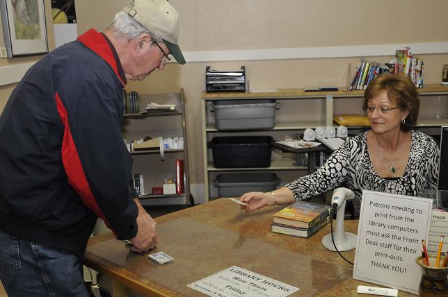 Clarkdale Human Resources and Communication Services Director Janet Perry checks out two books to Roger Dunn at the Clarkdale Public Library. Recently a survey was conducted in the town, asking what services residents use, what they would like to see and what they do not use.?