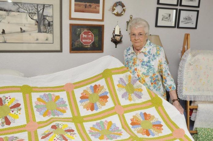 Local quilter Peg Miller holds up a queen size quilt she made from reproduction 1930s material, covered in designs known as Dresden Plates. Miller will be entering the quilt into Camp Verde’s October quilt show. In addition, 43 donated quilts will be sold during the show, with proceeds going to the library, the senior center and Camp Verde Historical Society Museum.