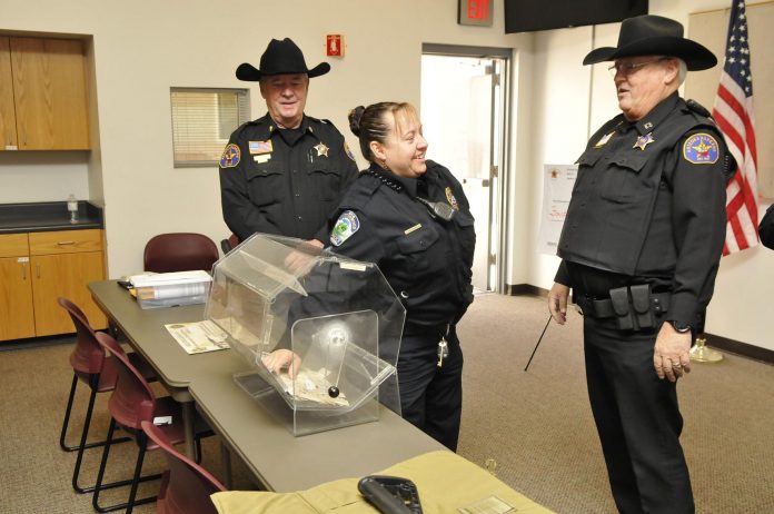 Flanked by Arizona Rangers Major Tim Cummings, left, and Capt. Gary Jordan, Cottonwood Police officer Sgt. Monica Kuhlt draws the winning ticket for a commemorative AZ Rangers carbine.