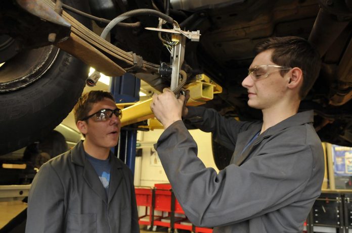 Mingus Union High School junior Ryan Rozeboon, right, stands under a Ford Explorer with senior Josh Wheeler, working to replace the vehicle’s fuel pump assembly. The fuel pump is located inside the gas tank, which had to be removed for the operation.