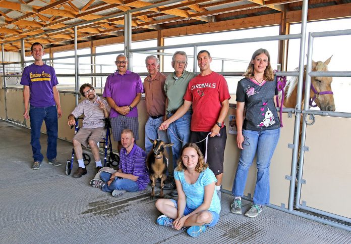 Residents of Rainbow Acres, known as ranchers, pose together in the on-property barn. The 50-acre Rainbow Acres facility houses over 90 developmentally disabled adults.