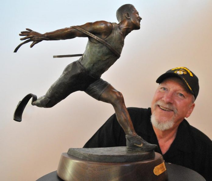 Clyde “Ross” Morgan, a bronze sculptor from Village of Oak Creek, showcases a miniature of his “Heroic Challenges” sculpture on Tuesday Aug. 27. A larger-than-life bronze is on permanent display at Veterans Sports Park in Prescott. Wounded U.S. Marine veteran Alex Minsky, served as the model for the statute. Minsky survived an improvised explosive device blast in Afghanistan, losing his leg and nearly his arm. Minsky has made headlines recently across the country with television interviews about overcoming his injuries.