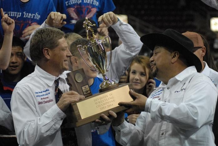 Bob weir, left, retiring head wrestling coach of Camp Verde High School, holds the Division IV state wrestling trophy with assistant coach Mario Chagolla, who will be running off-season camps and returning with new coach Tracy Tudor next season. Weir’s state title Saturday, Feb. 15, at Tim’s Toyota Center in Prescott Valley was his sixth in 22 seasons as coach of the Cowboys.