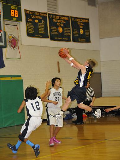 Chris Bean walks on air for a layup for Mountain View Preparatory Academy over Many Farms Community School eighth graders Trevor Wilson, No. 12, and Alonzo Bia, No. 24, during the Ocelots’ 37-26 loss to the Cougars at the small school state championships in Clarkdale on Friday, Feb. 7.