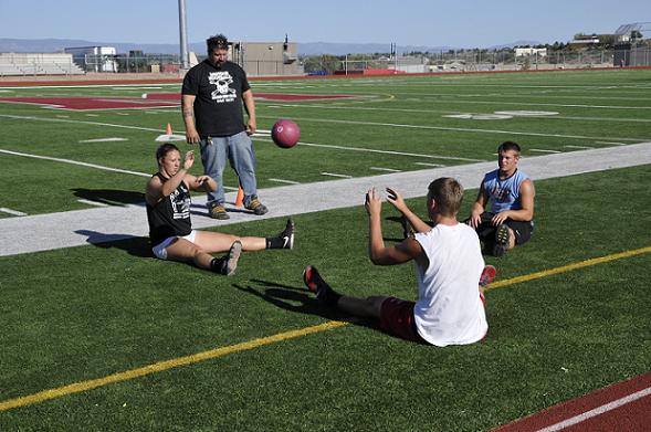 Mike DiQuattro, an assistant track coach for Mingus Union High School, supervises senior Heather Calandra, freshman Trevor Galloway and junior Levi Collins, from left, as they toss a medicine ball May 1, to develop upper body and core strength. Calandra was top in shot put and second in discus as the Marauders won their third straight state girls track title Saturday, May 10.