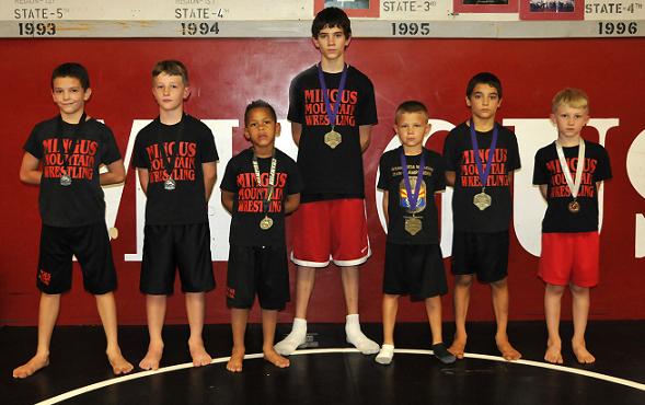 Elijah Miller, Isaac McKean, Koby Delahel, Trent Miller, Nathan Dixon, Kai Miller and Elias McKean, from left, Members of the Mingus Mountain Wrestling Club, wear a medal around their neck in the Mingus Union High School wrestling room for their performance at the preseason Under the Lights tournament Saturday, Oct. 4.,