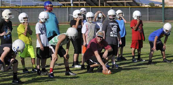 Assistant coach Jeremiah Littlepage, kneeling in the front, plays center to help the Camp Verde Middle School football team read his actions as well as his commands. The Cowboys, under head coach Brian Pelfrey, are practicing their first full week in helmets and shoulder pads in preparation for their first game Tuesday, Sept. 8.