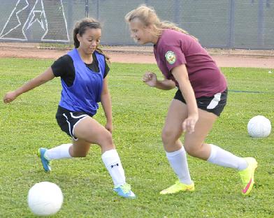 The Camp Verde High School varsity girls soccer team practices in preparation for a weekend tournament. Freshman Irlanda Lopez, left, kicks the ball out of senior Paige Church’s reach.
