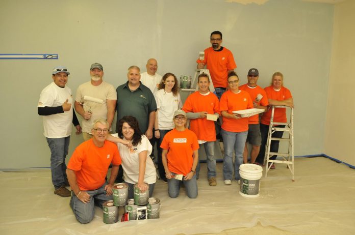 Home Depot donated $5,000 worth of paint and labor to repaint the inside of the Old Town Mission. The volunteers in orange pose with the mission staff, who were also wielding paint brushes and rollers.