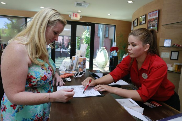 Megan Mejia, front desk agent at Sedona Rouge, helps Ashley Chancellor check into her room at the hotel. Mejia lives in Clarkdale and travels to Sedona every day to work, like many residents of the Verde Valley.
