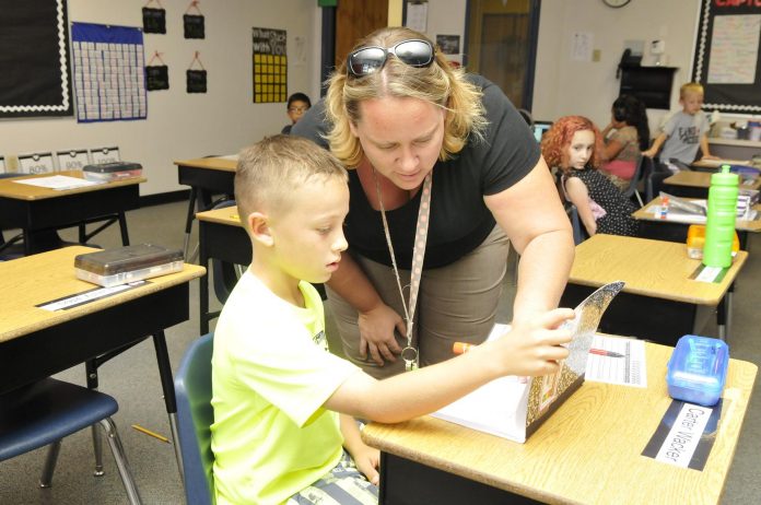 Angela Cox, a second-grade teacher at Dr. Daniel Bright School in Cottonwood, helps Carter Wacker, 7, with his math assignment. The state of Arizona is thinking of changing the English and Math standards at K-8 schools.