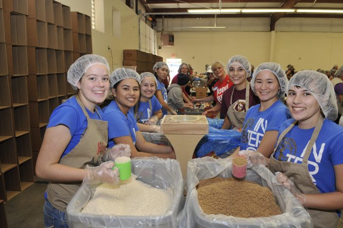 Junior Kylie Densmore, junior Dariana Portillo, Junior Mackenzie King, senior Maya Federbush, supervisor Dawn Canfield, freshman Felicia Buno, junior Saya Federbush, and junior Reanna Bueno, clockwise from right, all part-of the Mingus Union High School Interact Club, buisily work together to pack one of 300,000 meals, more than half of which will feed the hungry in the U.S., with the rest helping to end hunger in Haiti.