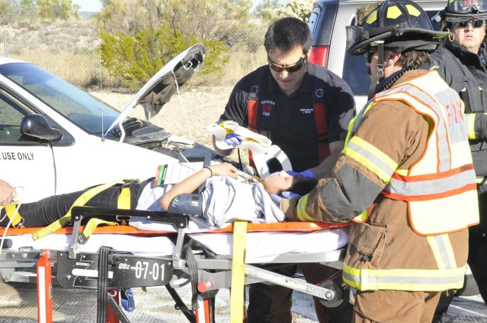 Firefighters from several agencies work together to apply a neck brace to a high priority car accident victim in a simulated car accident, staged at the northbound Interstate 17 rest area near Rimrock. The simulation had agencies dispatched to an accident involving several children.