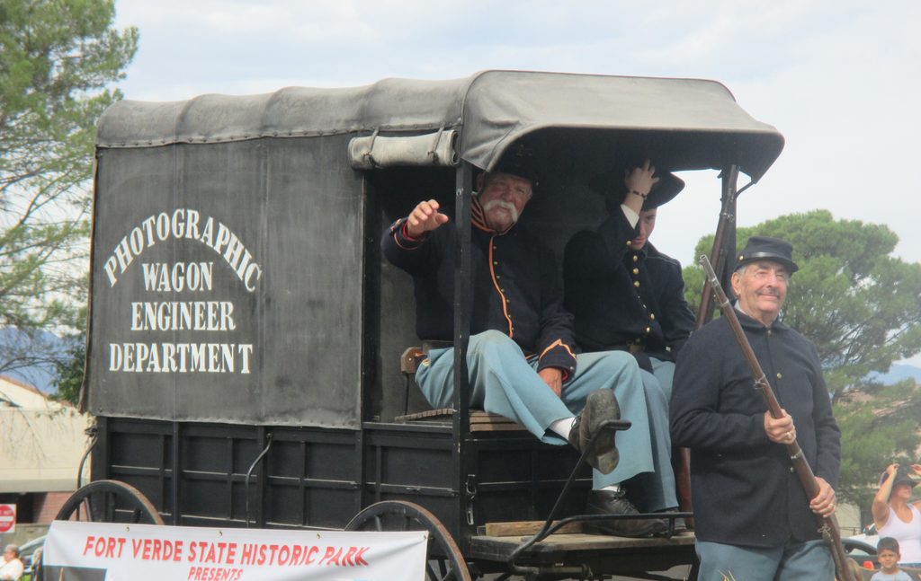 A man waves from a historical photographic wagon from the Fort Verde State Historic Park at the 70th Annual Fort Verde Parade on Saturday, Oct. 10, 2026.